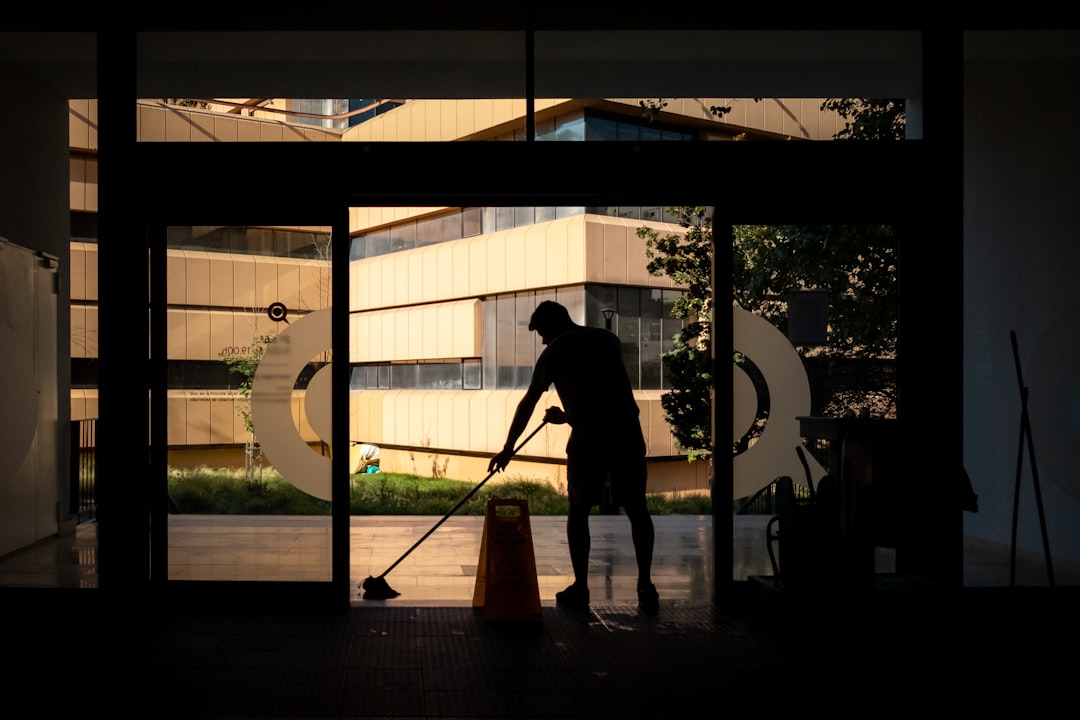 Man cleans floor at an entrance door.